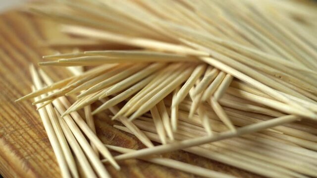 Scattered toothpicks. Wooden sticks. Means for cleaning teeth. Oral hygiene. Light wood. Rotation of the object. Macro.
