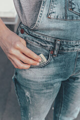 A womans hand takes out US dollar bills from her jeans pocket. The concept of finance, savings, financial expenses. Close-up. Vertical shot