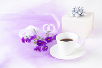 Obraz na płótnie Canvas レースのリボンと紫のペチュニアの花束とコーヒーと贈り物
