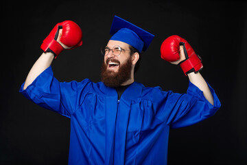 Excited bearded student man in blue bachelor celebrating with boxing gloves