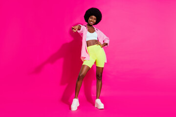 Photo of adorable pretty dark skin woman dressed crop top smiling dancing pointing finger you isolated pink color background