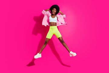 Photo of sweet funky dark skin lady wear casual shirt smiling jumping high isolated pink color background