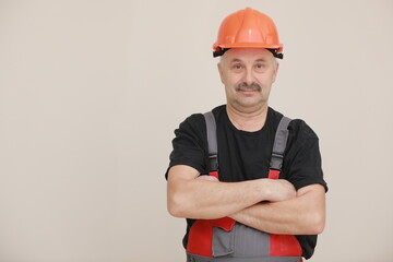 Construction worker in overalls and hard hat. Repairman with a mustache worker crossed his arms over his chest. Business, technology. Building concept. Studio shot on white background.