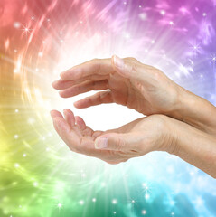 Healing energy contains all the colours of the rainbow and appears white - female healers cupped hands surrounded by glowing white and bright coloured light with copy space

