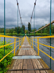 Perspective view of suspension bridge over river on cloudy day