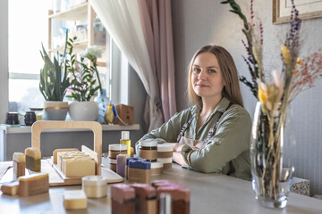 A woman soap maker lays out and packs freshly prepared handmade soap and body care cosmetics. The...