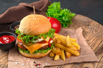 Homemade burger with beef, cheese and vegetables on a brown background. Fast food. Horizontal view, space for copying.