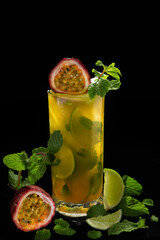 Closeup glass of Mojito with passion fruit ( maracuya ) lime and green leaf mint isolated on black...