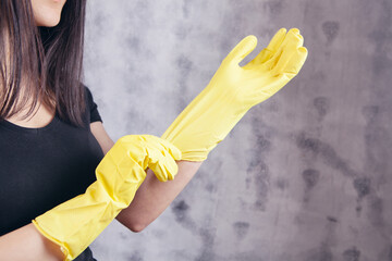 young woman puts on yellow rubber gloves