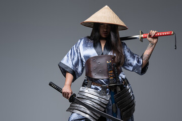Young female warrior with samurai swords and bamboo hat