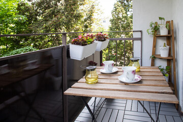 bright small apartment terrace in summer with flowers and coffee table