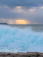 Ray of light over the wave breaking on the coast.