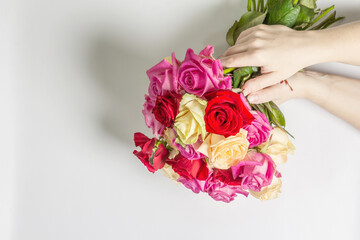 The woman's hands are holding a beautiful bouquet of fresh multicolored roses