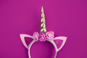 Unicorn horn on a rim with flowers and ears on a colorful background. View from above.