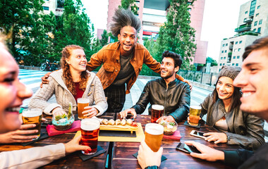 Young people drinking beer at brewery bar dehor - Friendship lifestyle concept with multicultural friends spending happy hour time together at open air pub garden - Warm bright filter