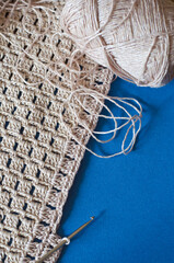 Crochet with beige cotton threads on a blue background.