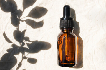 Glass bottle with a pipette close up in the rays of the sun.