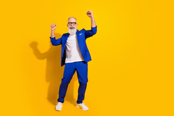 Full length photo of happy cheerful old man raise fists winner wear blue tuxedo isolated on yellow...