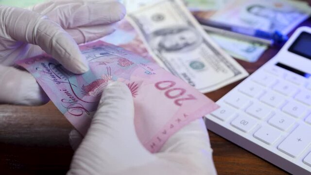 Hands inspection ukrainian money hryvnia for counterfeit money. Count banknote bill currency. Currency denomination note on brown desk background. Business or financial concept. Money or cash revenue