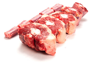 Raw uncooked beef oxtail cut into portions on white isolated background. Butcher craft. Meat industry product. Soup and stew ingredient