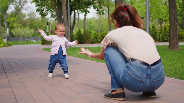 Baby girl takes first steps. Concept of family summer vacation, outdoor games, first steps, child development