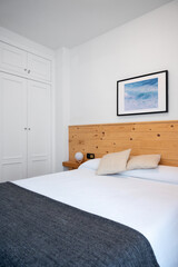 Bright white bedroom interior decorated with a photo of sea waves and a wooden headboard