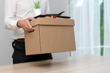A businessman holds a box for personal items after sending a resignation letter to an executive or...