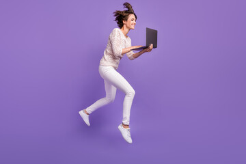 Fototapeta na wymiar Full length photo of pretty funny young woman wear knitted shirt jumping high typing modern gadget isolated violet color background