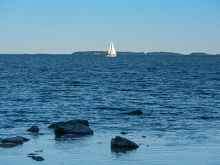 A sailboat sailing across the horizon during sunset.