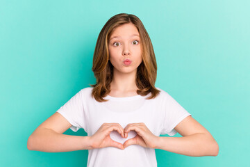 Photo portrait little girl happy showing heart sign with pouted lips sending air kiss isolated vivid turquoise color background