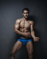 Fototapeta premium Shirtless man in blue underwear at grey background in studio