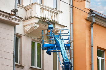 Worker repairing balcony, historic architecture of old facade. Plaster cladding and crack repairs....