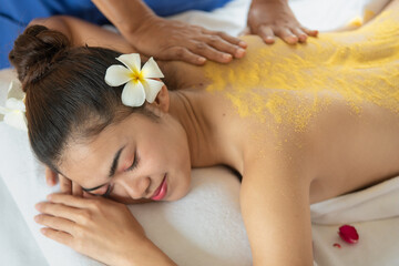 Beautiful Asian woman having exfoliation treatment with body scrub in spa salon, scrubbing and skin care concept, enjoying and relaxing time