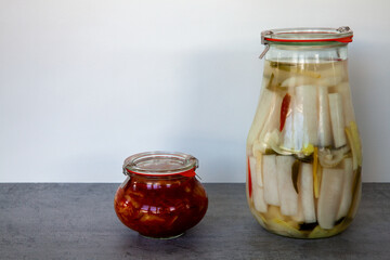 Two different versions of Korean Kimchi in glass jars: white radish Dongchimi and Gochugaru napa cabbage traditional fermented food.