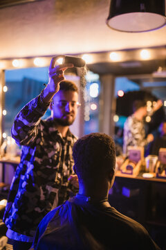 Barber pouring styling powder on head of black man
