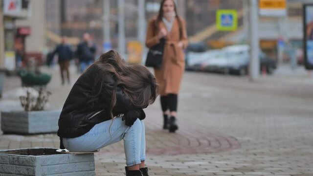 The girl is crying on the street of the city. A sympathetic passer-by calms a lonely girl.