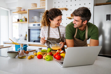 Young happy couple is enjoying and preparing healthy meal in their kitchen
