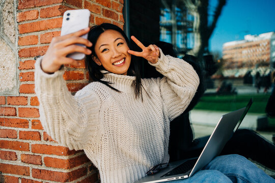 Positive Asian Female Millennial Taking Selfie While Using Laptop On Street