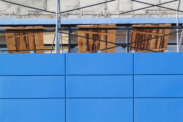 Metal scaffolding against wall of shopping center under construction. Concept of building construction, exterior wall decoration with blue ventilated facade.