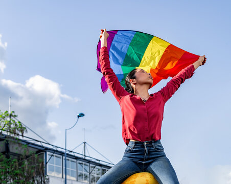 Asian woman waving LGBT flag on street