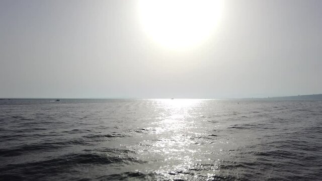 Travelling sur la mer bleue p&eacute;trole en contre jour face au soleil avec des bateaux &agrave; l'horizon