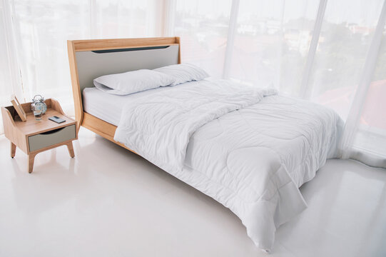 The white bed in the bedroom, there are white curtains around the room.