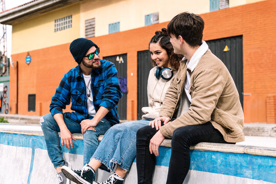 Young students talking and smiling on urban parapet