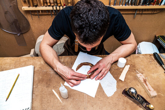 Faceless craftsman putting wooden pieces on paper in workshop