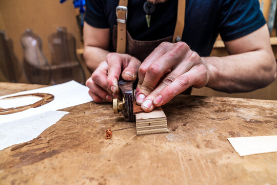 Crop craftsman cutting wooden block with file in workshop