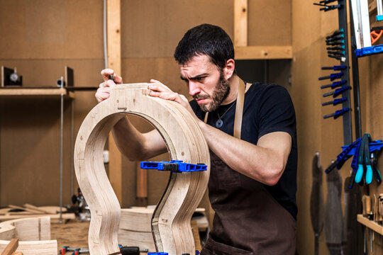 Luthier building guitar at table in workshop