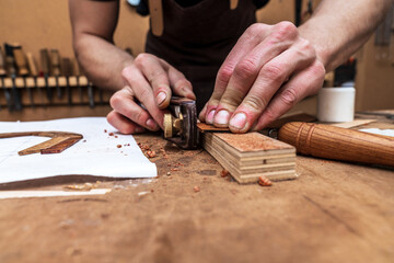 Crop luthier cutting wooden piece with plane in workroom