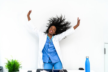 Black female doctor in medical uniform dancing in clinic