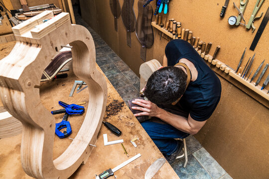 Focused artisan working with wood while building guitar