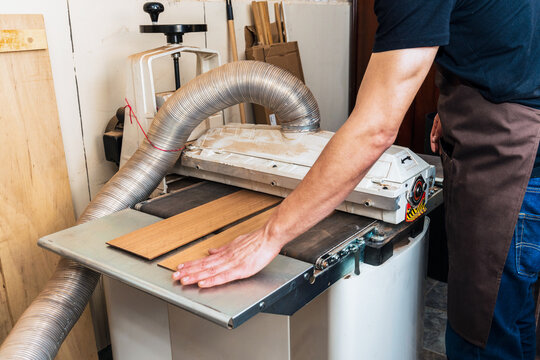 Crop luthier flattening wooden planks on planer in workroom